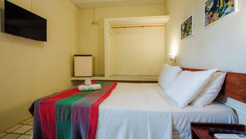 A hotel room with a bed, a television mounted on the wall, and artwork on the wall.