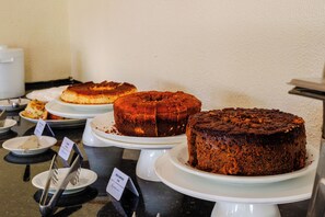 Un bufé con diversos pasteles y postres sobre platos blancos.