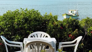 Vista de un barco llamado 'Feliz Portos' en aguas tranquilas, con vegetación exuberante al frente y un cielo despejado.