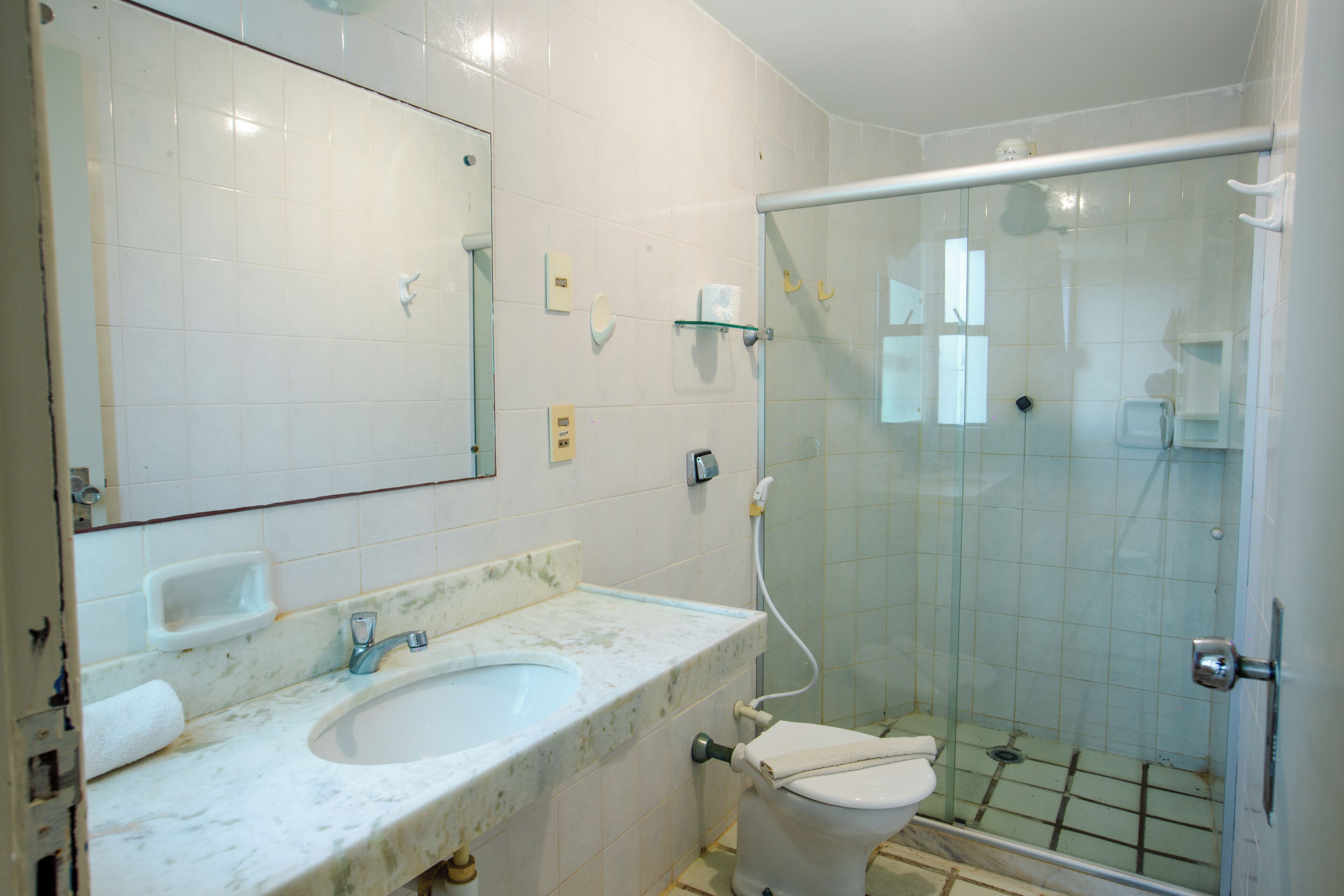 A bathroom with a white sink, mirror, and glass shower enclosure.