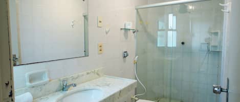 A bathroom with a white sink, mirror, and glass shower enclosure.
