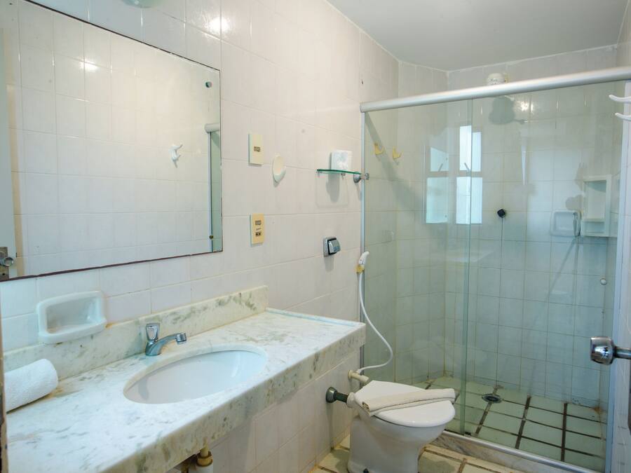 Un baño con lavamanos blanco, espejo y cabina de ducha de vidrio.