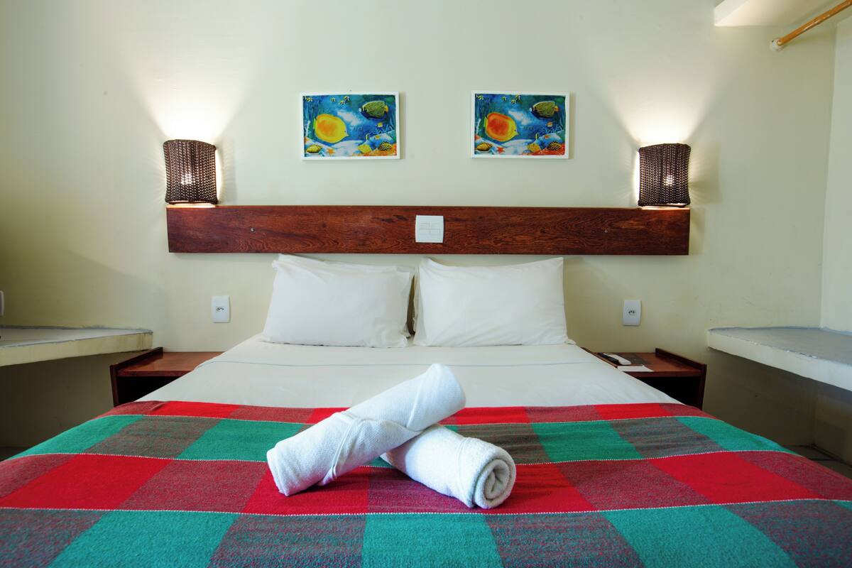 Ein Hotelzimmer mit einem großen Bett, zwei Bildern an der Wand und zwei Wandlampen.