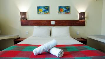 A hotel room with a large bed, two paintings on the wall, and two wall-mounted lamps.
