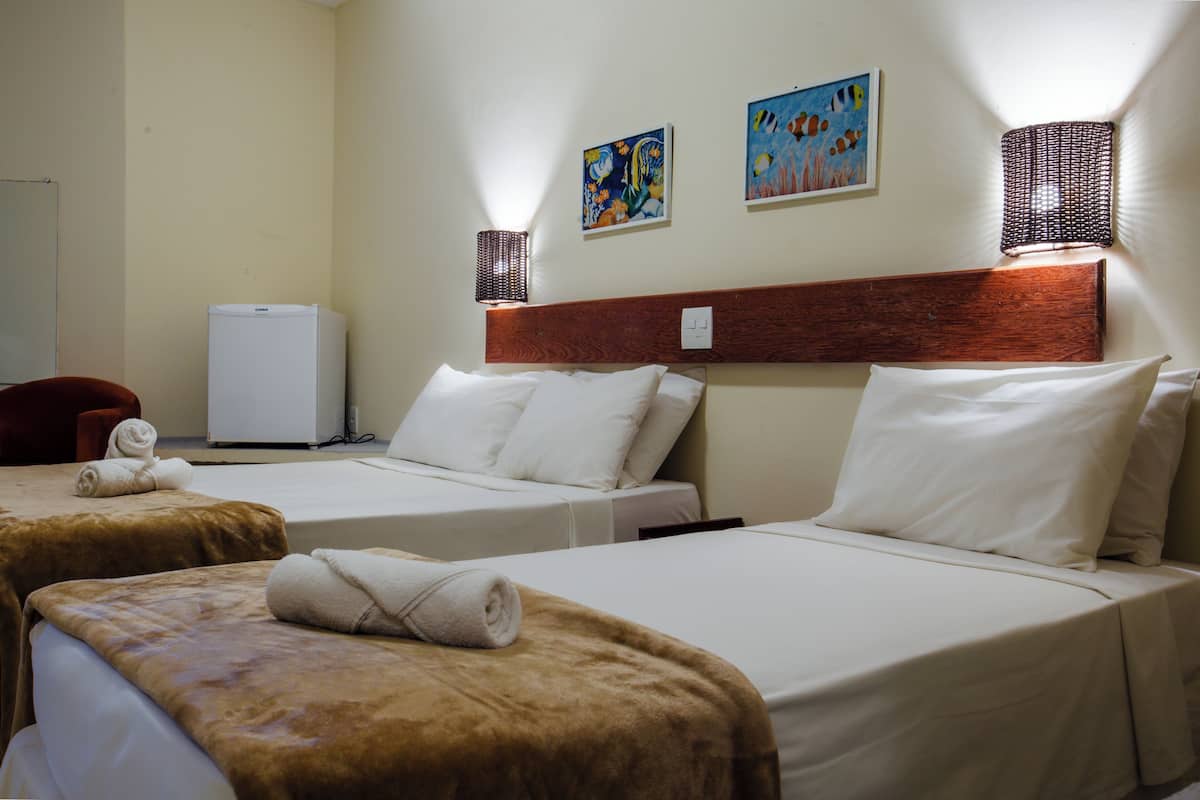 Ein Hotelzimmer mit zwei Betten, einem Kühlschrank und Bildern an der Wand.