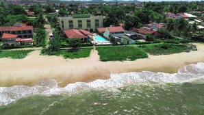 Una propiedad frente a la playa con piscina, un edificio grande y una playa de arena.