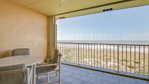 A balcony with a view of the beach, a round table, and two chairs. - Oceanfront Condo, Private Walkway to the Beach by RedAwning (Fernandina Beach)