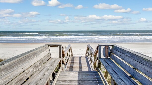 A wooden boardwalk leading to a beach with a wooden bench and a railing. - Ocean View Condo, Easy Acces to the Pool and Private Walkway to the Beach by RedAwning (Fernandina Beach)