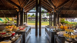 A buffet setup with various food items and a view of a beach and palm trees.