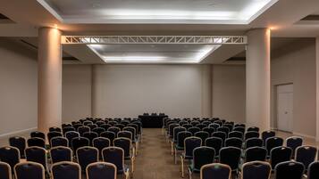 A conference room with rows of chairs, a podium, and a ceiling light fixture.