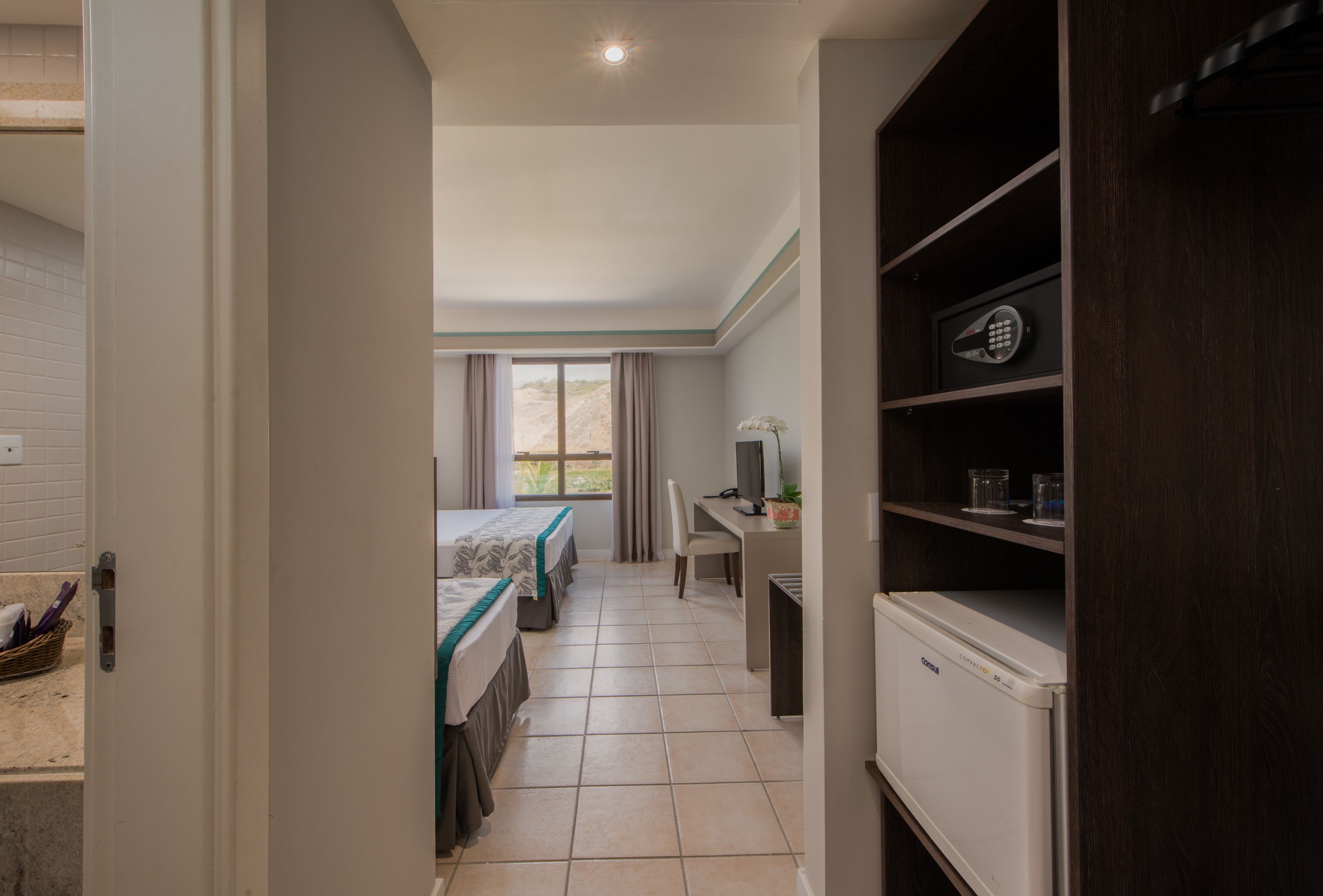 A hotel room with a bed, desk, and a refrigerator.