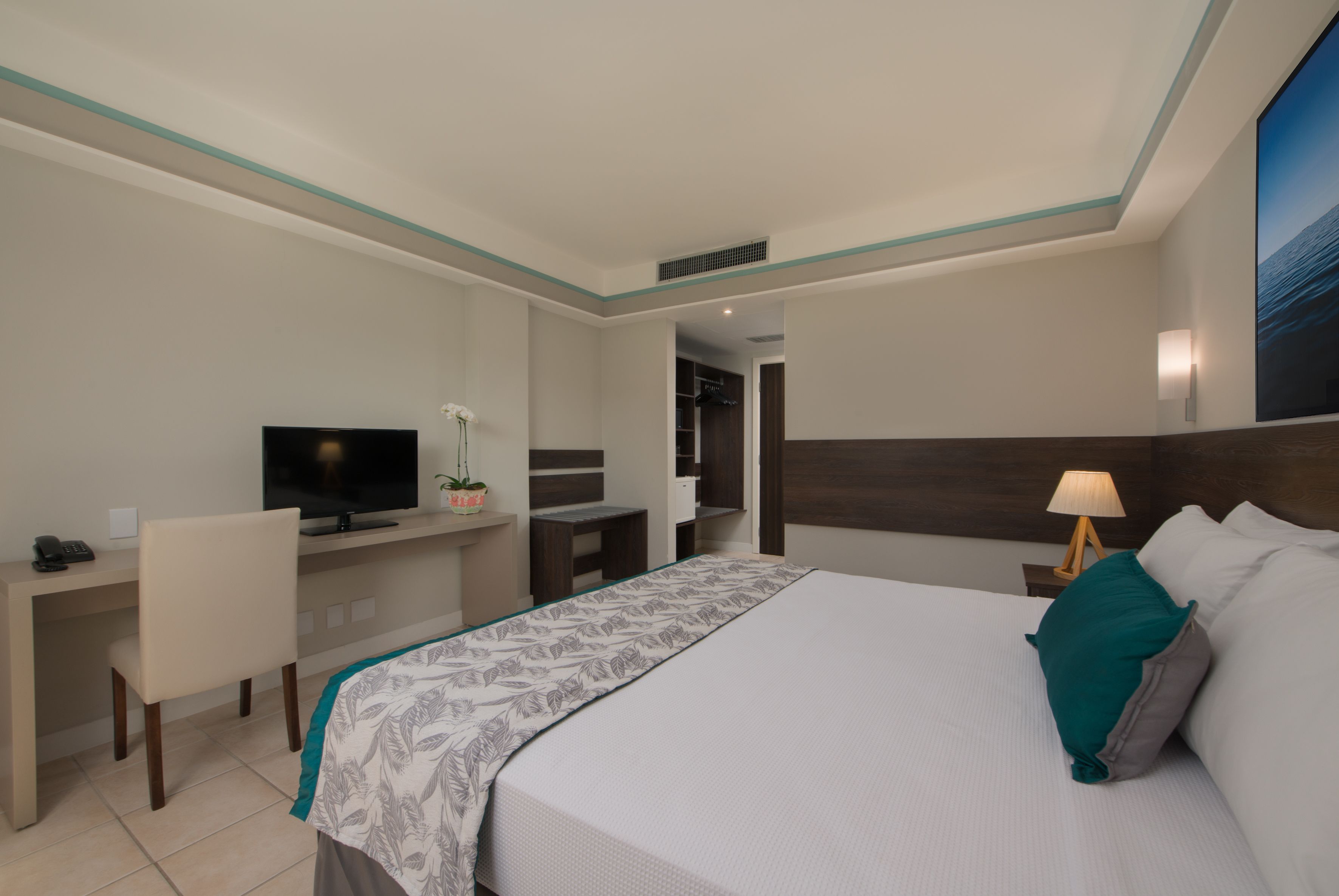 Una habitación de hotel con cama, escritorio, televisión y mesita de noche.