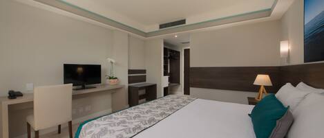 A hotel room with a bed, a desk, a television, and a nightstand.