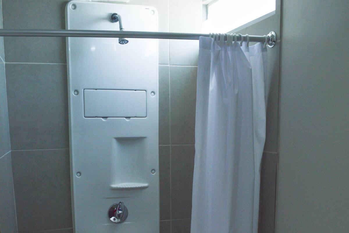 Une salle de bain avec une douche, des toilettes et un porte-serviettes.