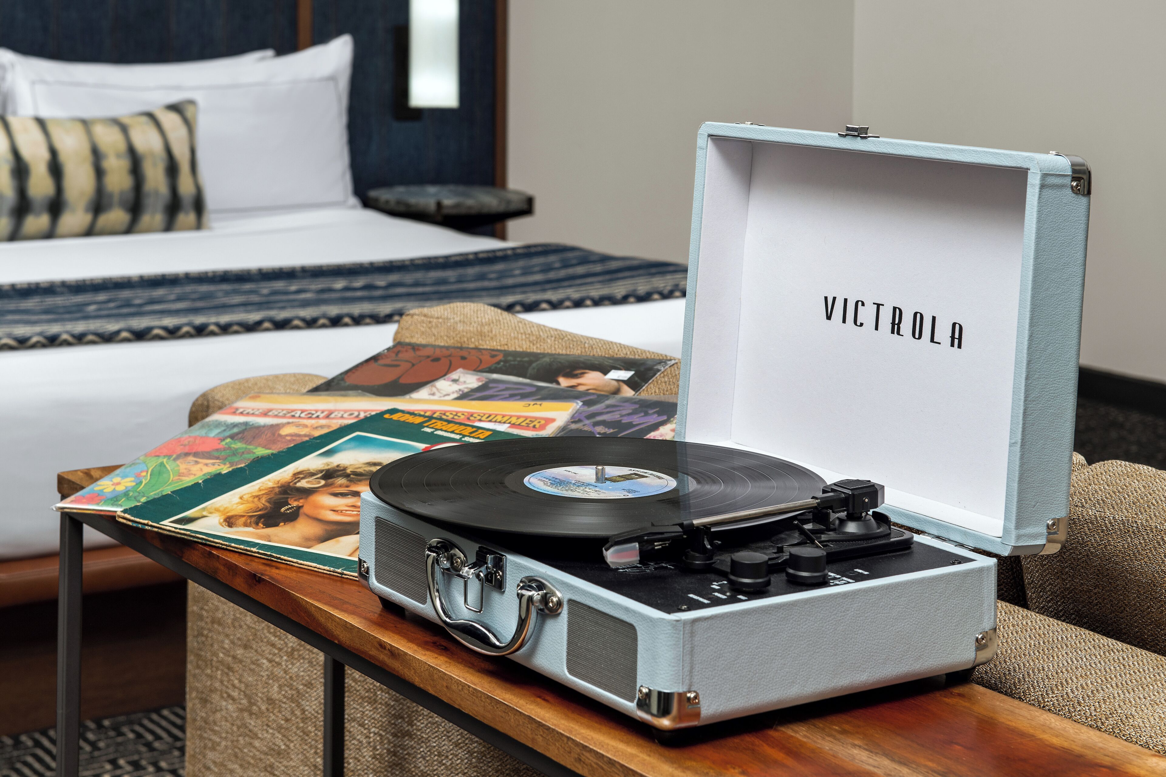 Une platine vinyle ancienne, avec un disque en vinyle posé sur une table en bois, dans une chambre d’hôtel.