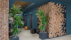 Un vestíbulo moderno con un revestimiento de pared de madera, dos plantas en macetas y un suelo de baldosas.