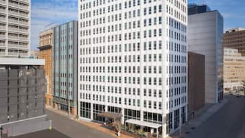 A modern hotel with a grid of windows, a covered entrance, and a parking lot.