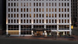 Un hotel de varios pisos con una fachada simétrica, ventanas grandes y una entrada central con toldo.