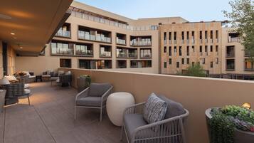 A modern outdoor patio with wicker furniture, a round seating area, and a view of the building's balconies.