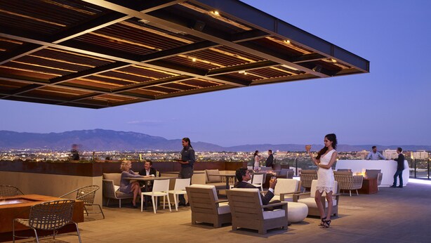 An outdoor seating area with a view of the cityscape and mountains. - Hotel Chaco (Albuquerque)