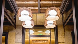 A lobby with a modern design, featuring a large glass entrance, a central art piece, and two large hanging lamps. - Hotel Chaco (Albuquerque)