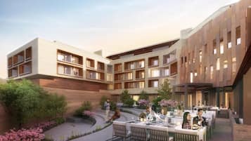 A modern hotel with multiple floors, outdoor dining area, and landscaped garden.