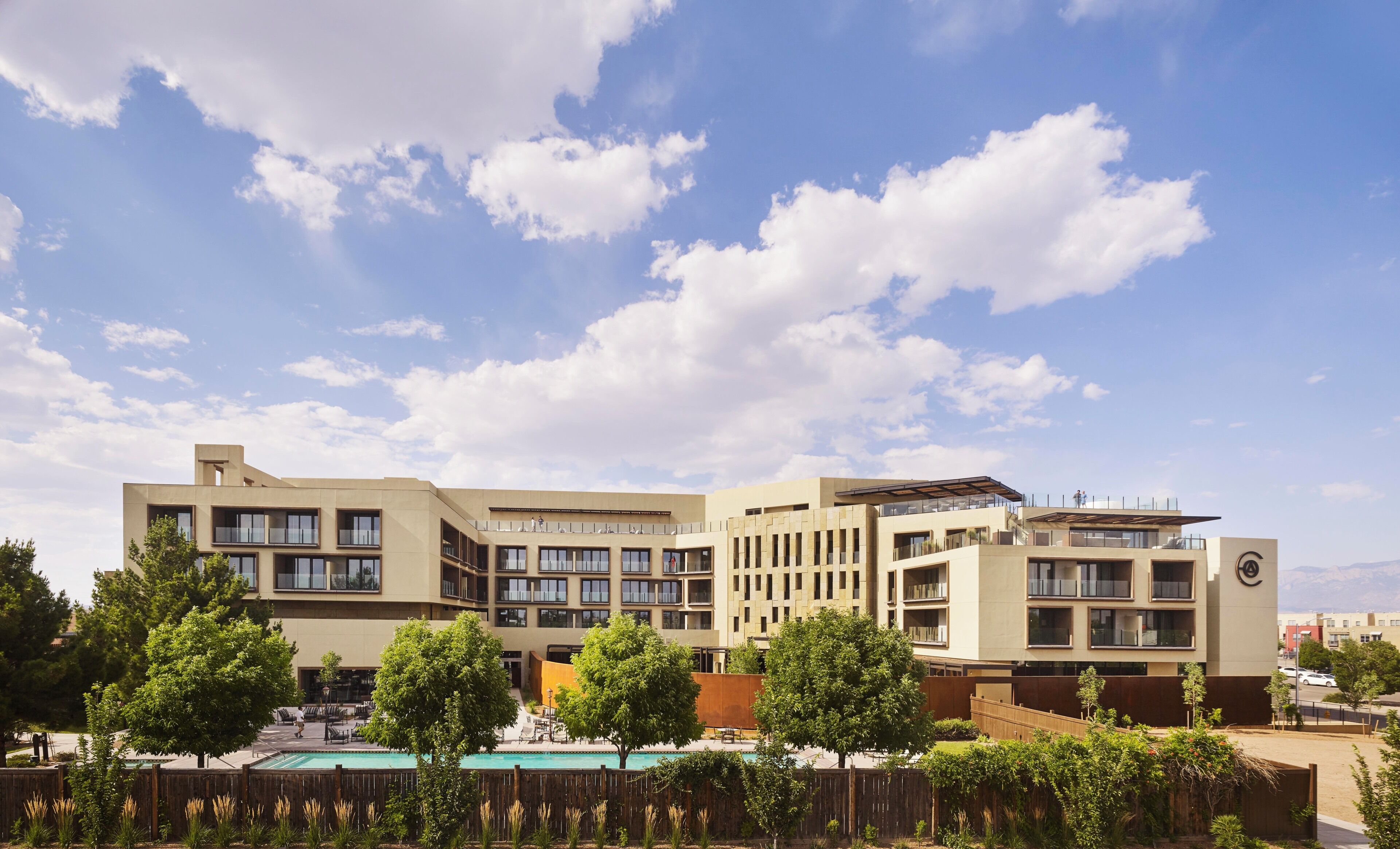 A modern hotel with multiple floors, outdoor pool, and landscaped areas.