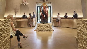 A lobby with a central sculpture, stone walls, and a high ceiling with a decorative pattern. - Hotel Chaco (Albuquerque)