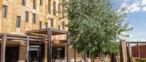 Un bâtiment moderne doté d’une cour intérieure aménagée avec des espaces de détente en plein air, un foyer et un arbre.
