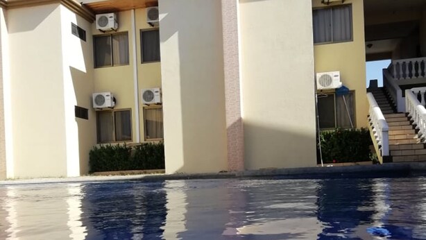 En bygning med flere klimaanlæg, en pool med klare spejlbilleder og en trappe op til en etage.