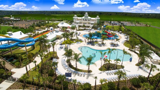 A resort with a large pool, water slides, and a golf course in the background. - Encore Resort Vacation Homes & Waterpark (Kissimmee)