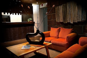 A cozy living area with a wooden coffee table, a black vase, and an orange sofa.