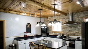 Cozinha moderna com ilha central, eletrodomésticos de aço inoxidável e vigas de madeira no teto.