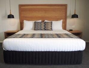 A bed with a wooden headboard, two bedside tables, and two pendant lights. - Euston Motel (Euston)