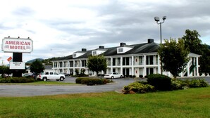 A motel with a sign reading "AMERICAN MOTEL" and a parking lot with several cars. - American Motel (Lenoir)