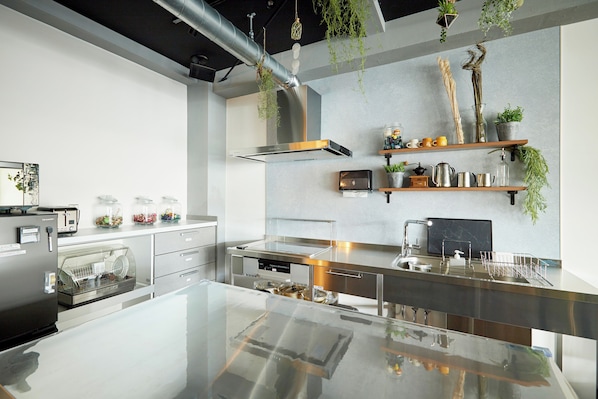 Uma cozinha moderna com eletrodomésticos de aço inoxidável, uma ilha de vidro e plantas penduradas.