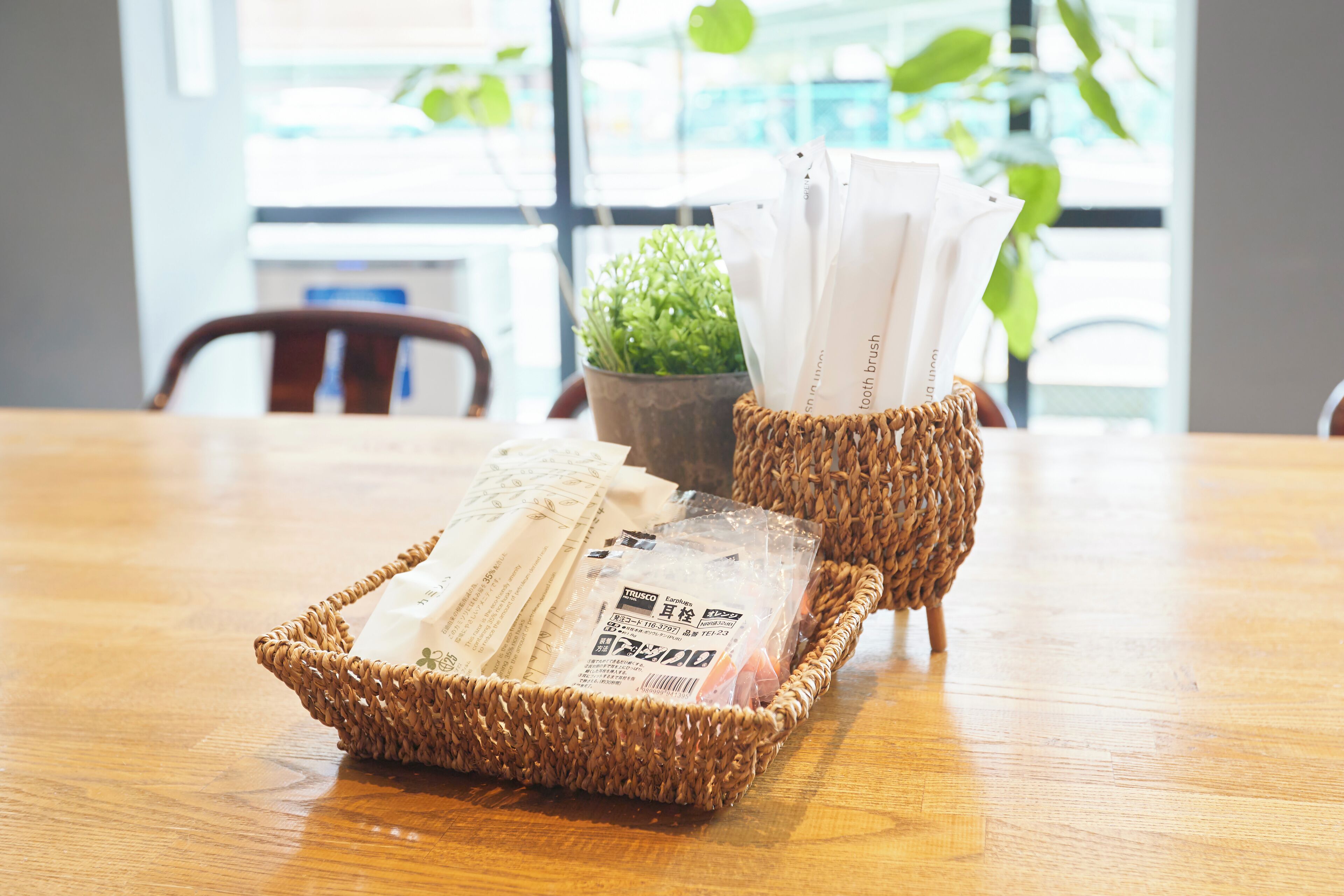 A wooden table with a woven basket containing a toothbrush and a plastic bag.