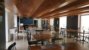 A spacious dining area with high wooden ceilings and a mix of white and dark chairs. - Hotel Catedral (La Paz)