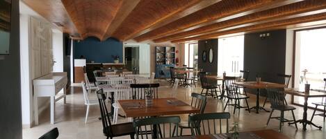 A spacious dining area with high wooden ceilings and a mix of white and dark chairs.