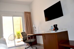 Habitación de hotel con escritorio, silla, televisión y vistas al exterior.