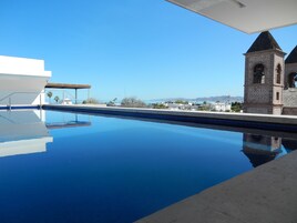 A clear blue pool with a view of a building and distant mountains.
