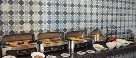 A buffet setup with multiple serving stations and a patterned tile backsplash.