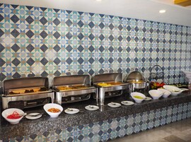A buffet setup with multiple serving stations and a patterned tile backsplash.