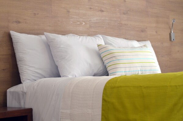Una cama con ropa de cama blanca y una manta verde.