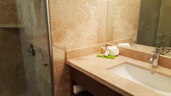 Un baño con lavabo, espejo y zona de ducha.