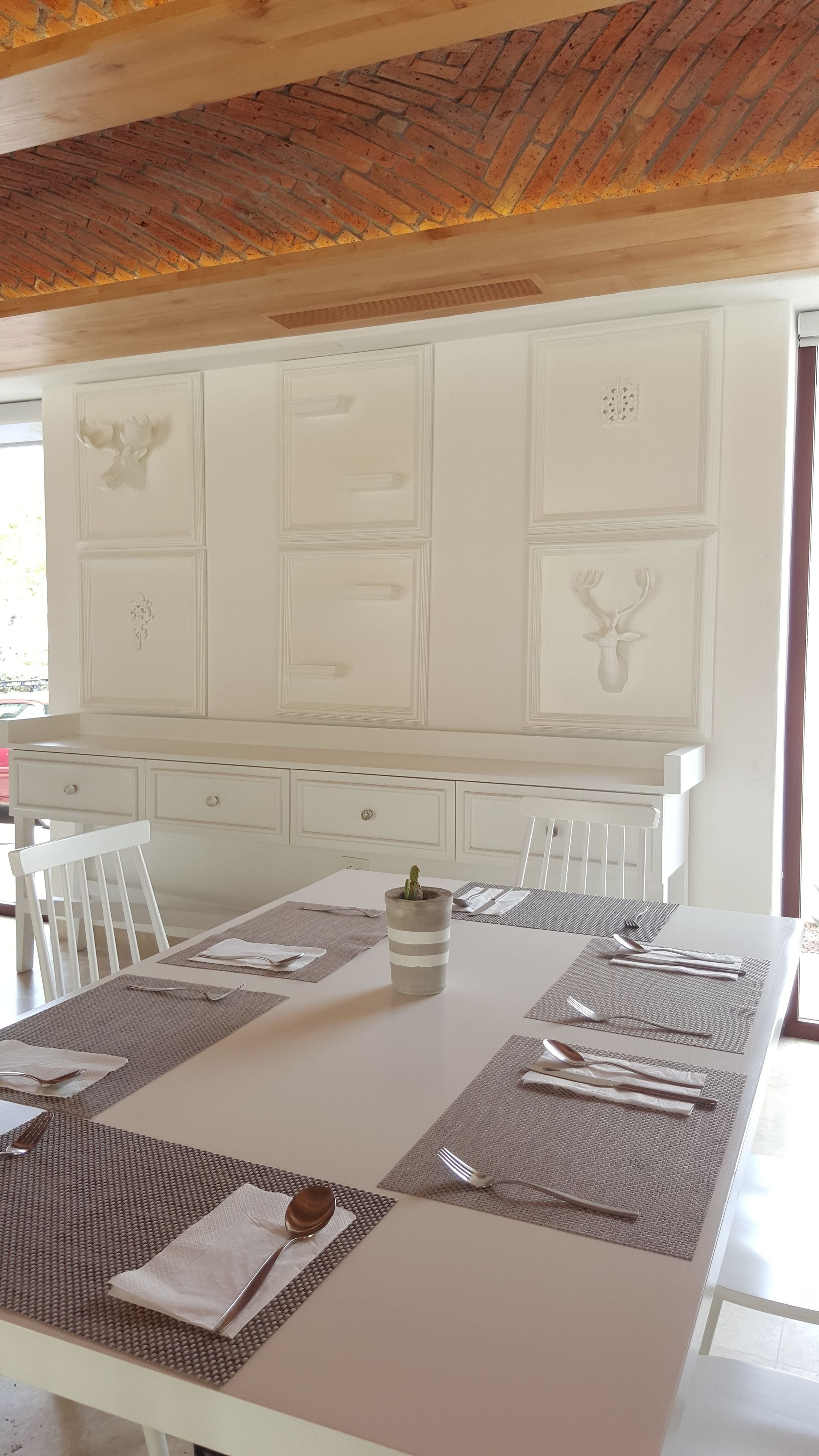 A dining area with a white table set for four, including place settings and a cactus centerpiece.