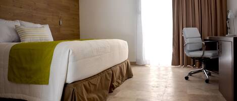 Una habitación de hotel con una cama, un escritorio y una silla.