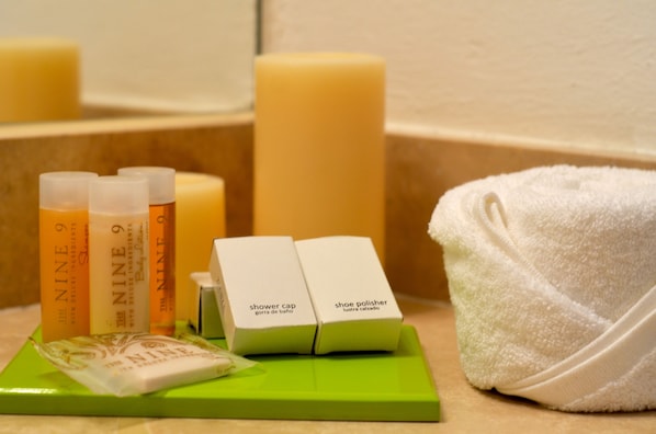 A bathroom vanity with toiletries including a green soap dish, a white towel, and several bottles of shampoo and conditioner. - Hotel Catedral (La Paz)