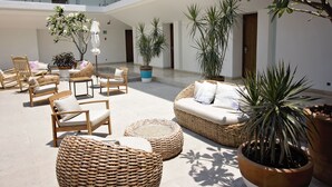 A spacious indoor area with wicker furniture, potted plants, and a glass railing overlooking the interior. - Hotel Catedral (La Paz)