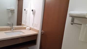 Une salle de bain équipée d’un lavabo, d’un miroir, d’un porte-serviettes et de deux sèche-cheveux.